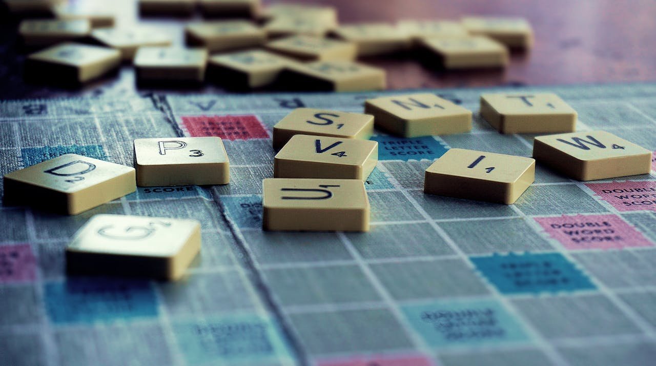 Close-up of Scrabble tiles scattered on the board, capturing leisure and word play.
